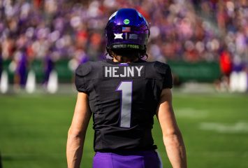 Photograph of TCU quarterback Hauss Hejny, pictured from the rear. Hejny, wearing a purple TCU helmet with a black jersey and purple pants, looks straight ahead.