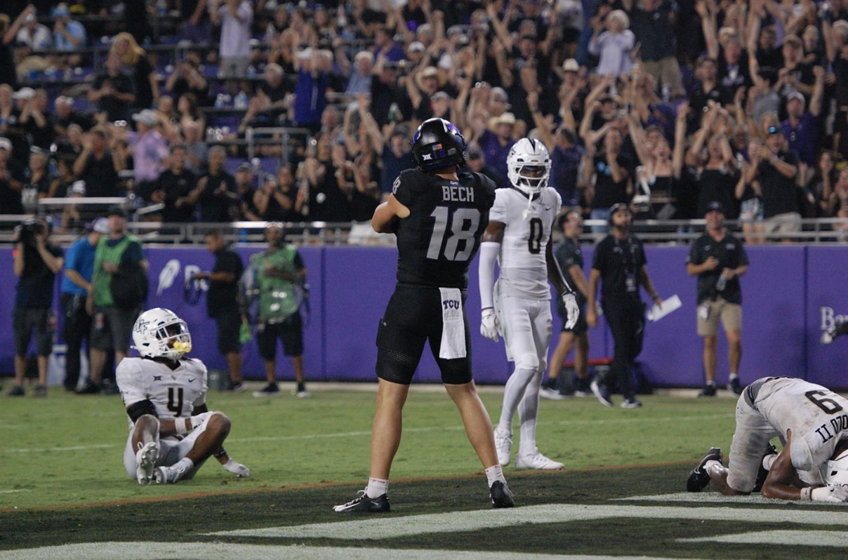 TCU football player Jack Bech celebrates a 50-yard touchdown during TCU’s Sept. 14 game against UCF. Bech stands confidently with his arms crossed over his chest, while three UCF defenders react in dismay — one lies face-down with his head in his hands, another sits on the ground looking up at the jumbotron, and the third glances toward Bech.