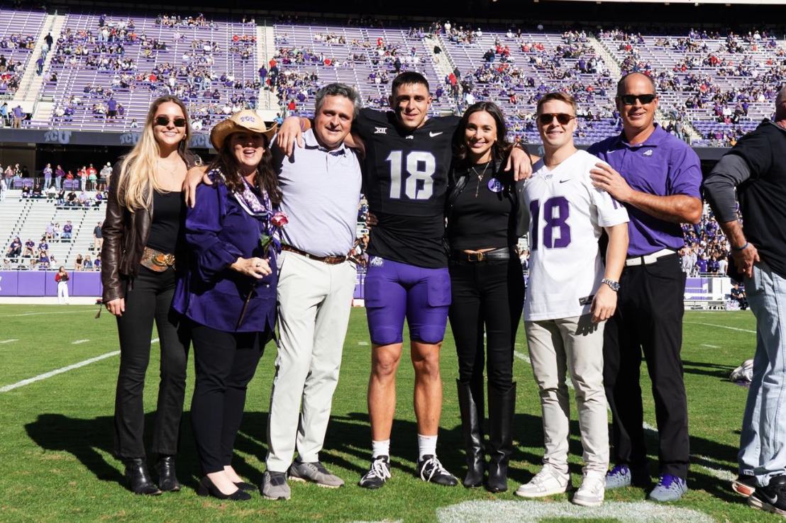 TCU student-athlete Jack Bech stands with his family during TCU Football’s 2024 Senior Day pre-game celebrations. Seven people smile under bright sunlight, with the stadium’s purple seats and scattered fans filling the background.