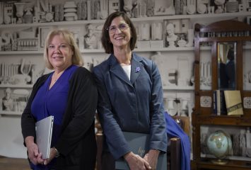 Photograph of Neeley researchers Patti Jordan and Laura Meade standing and smiling against a white shelf backdrop.