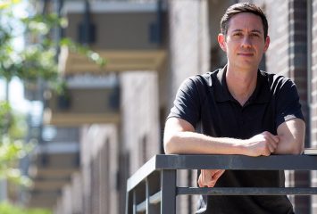 Zack Hawley, associate professor of economics, stands at The Cooper Apartments on West Rosedale Street