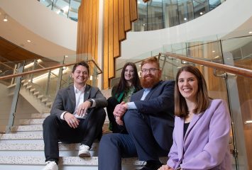 Faculty members pose on the first floor stairs of the Dan G. Rogers Rotunda.