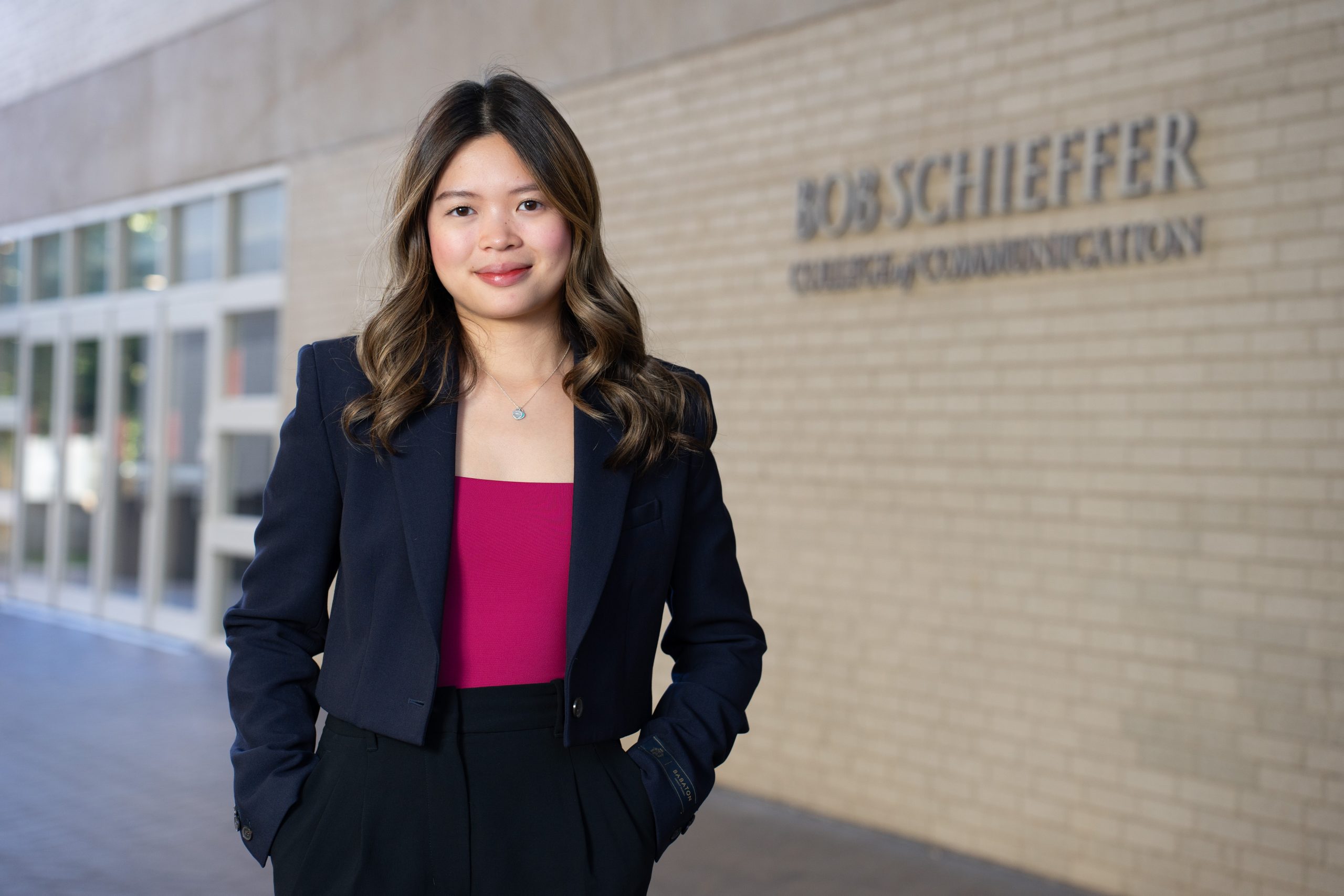 TCU student Cecilia Le standing beside the Bob Schieffer College of Communication.