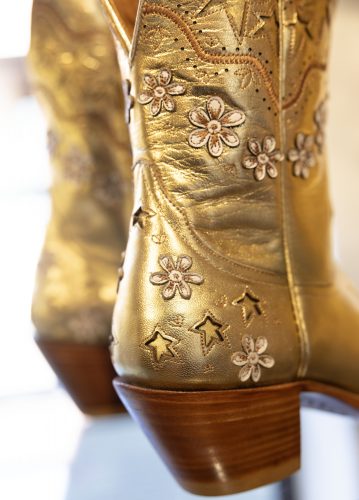 Close-up of the back of a pair of golden cowboy boots with wooden heels.