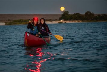 Photograph of two TCU students paddling by canoe on Benbrook Lake.