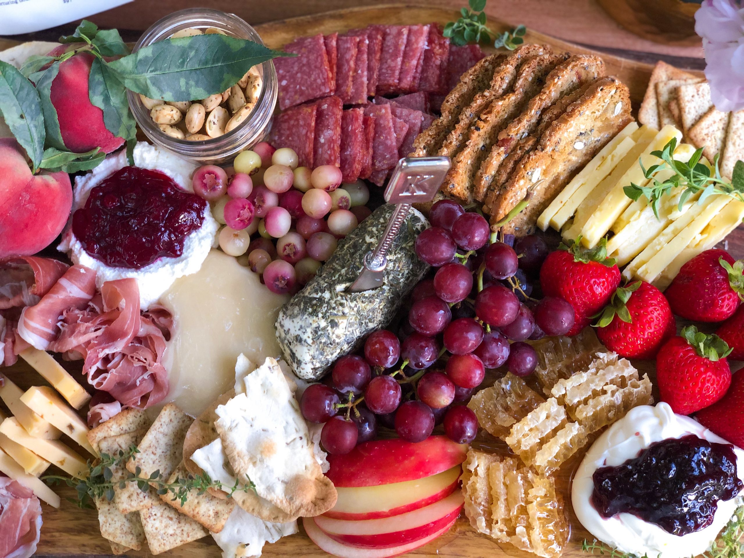 A table spread with an assortment of grapes, cheeses and cold-cut meats.