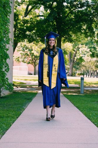 Photograph of former TCU student Randie Speir walking down a sidewalk in a graduation robe.