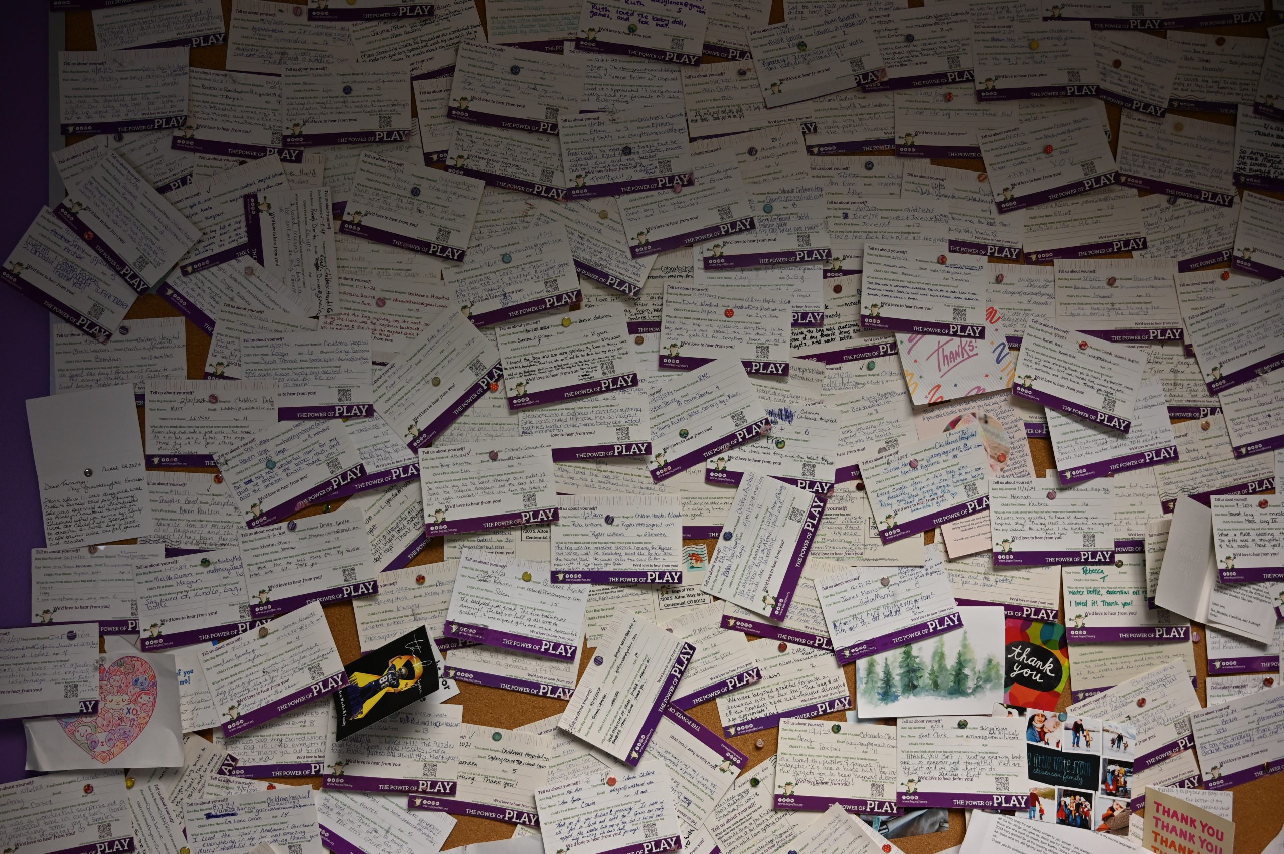 Photograph of children's thank-you cards pinned to a corkboard, written by recipients of Bags of Fun.