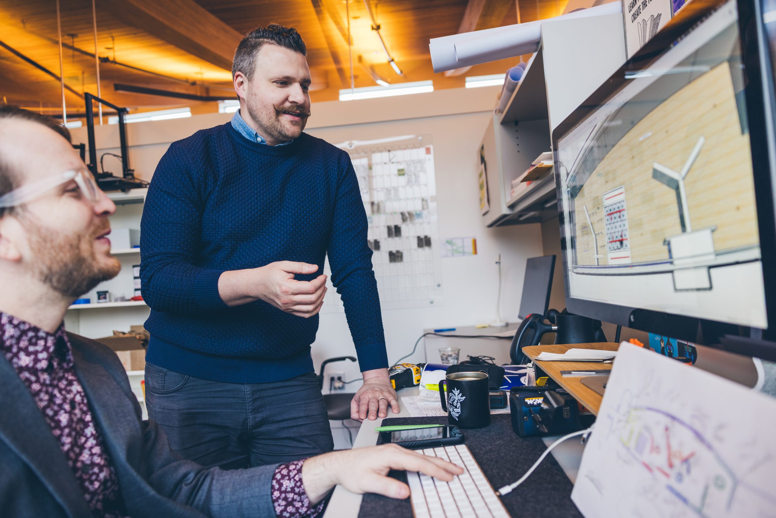 Photograph of Alejo Benedetti and Landon Perkins, a member of Crystal Bridges’ exhibition design team, reviewing plans for the museum’s new contemporary wing together at a desk.