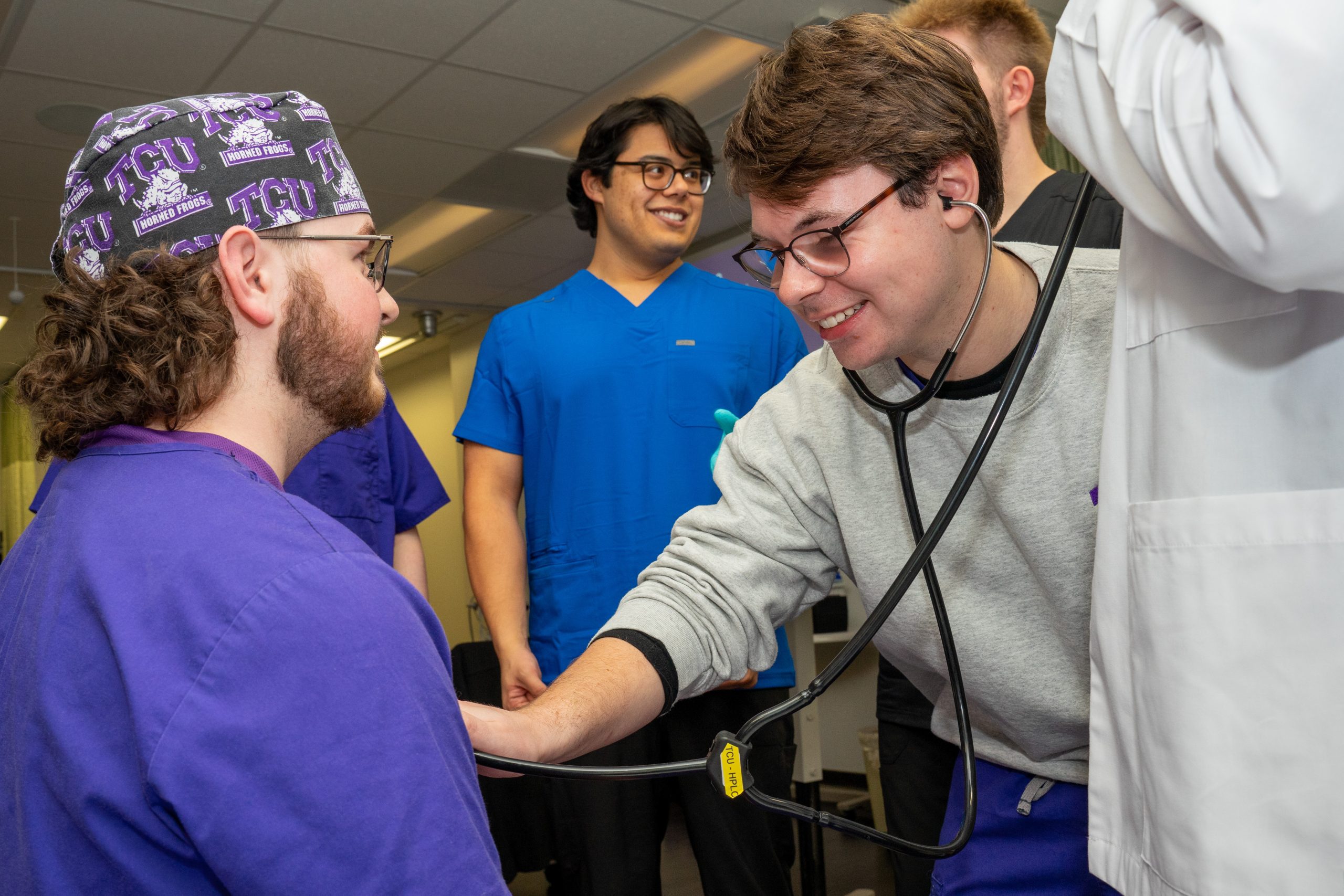 Photograph of TCU male nursing students practicing physical exam skills.