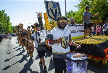 Photograph of people dressed in Vegas Golden Knights attire and holding team signs while participating in a parade.