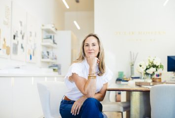 Portrait of Julie Rootes, TCU alumna and founder of Julie Rootes Interiors, seated facing the camera with her right hand resting below her chin and left hand in her lap.