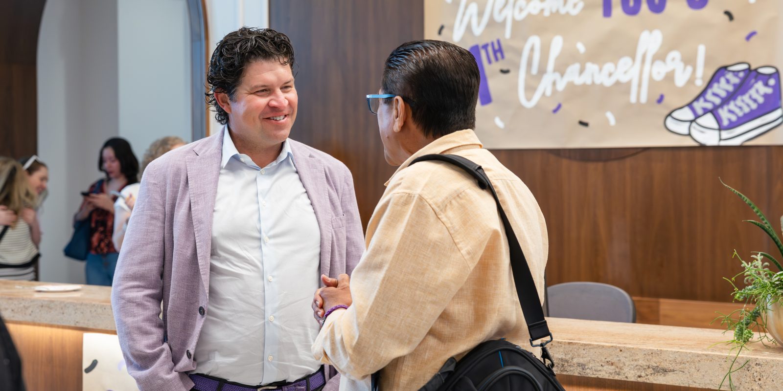 TCU Chancellor Daniel Pullin speaks with a campus community member on his first day in the role in 2025, during an event in the Harrison building.