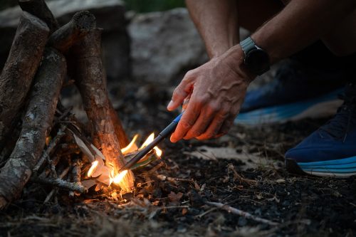 Detail shot of Brian Miller’s hands sparking a campfire with a fireplace-style lighter.