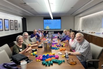 Photograph of members of Texas Christian University’s Quinq Club — alumni who graduated at least 50 years ago — seated at a long wooden table covered with colorful plastic Easter eggs.