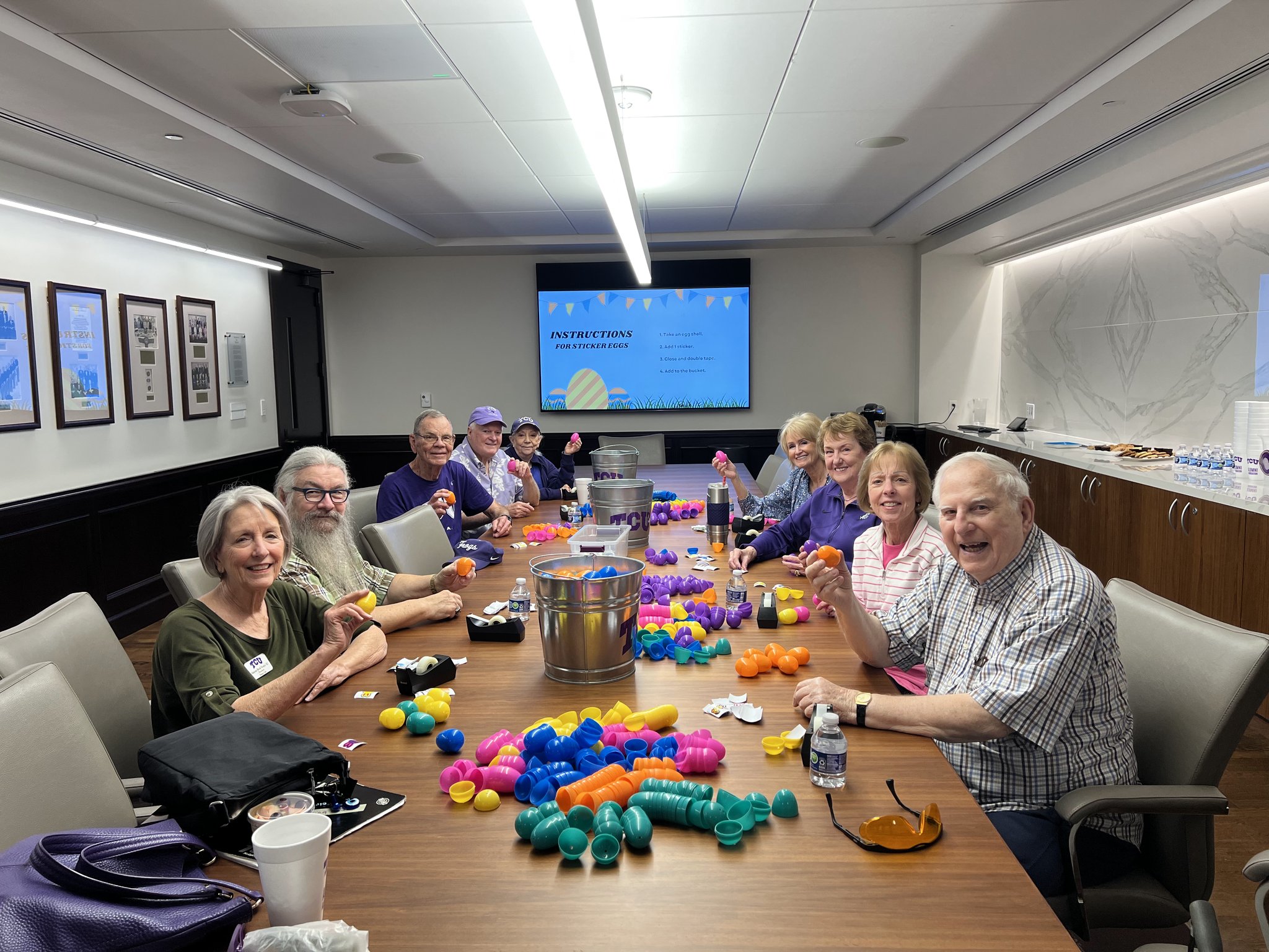 Photograph of members of Texas Christian University’s Quinq Club — alumni who graduated at least 50 years ago — seated at a long wooden table covered with colorful plastic Easter eggs.