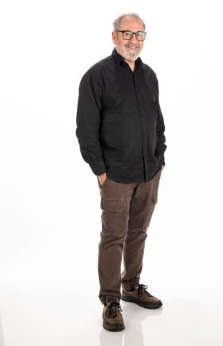 Photograph of TCU professor and entrepreneur Michael Sherrod standing against an all-white pop-up background. Sherrod has a smile on his face, with his hands resting in his pant pockets.