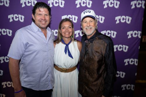 Daniel and Ann Bluntzer Pullin celebrate the start of his tenure as TCU chancellor with country music legend Robert Earl Keen, smiling in front of a TCU-themed press-conference-style backdrop.