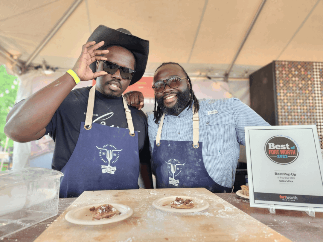 Photograph of brothers Reggie (left) and Cedric Robinson standing behind a table with two plates of food. Both are smiling — Reggie holds his right hand to his sunglasses, while Cedric leans slightly toward his brother.