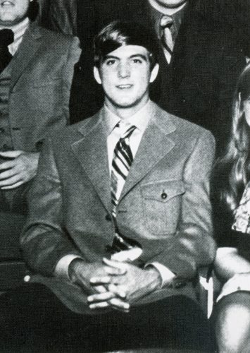 Photograph of Clarence Scharbauer III during his time as a TCU student. He is wearing a sports jacket, dress shirt and tie, with his hands clasped together over his lap.