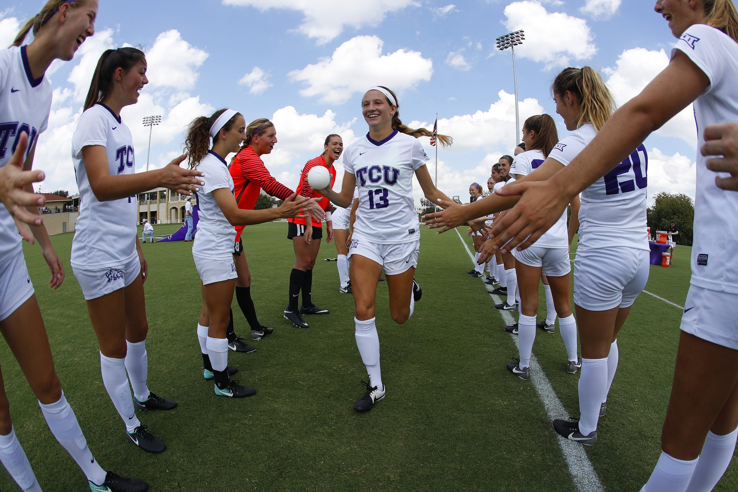 Photograph of soccer player Ryan Williams as a TCU student-athlete, running through a tunnel of teammates on the field before a Horned Frog soccer game on a slightly cloudy day.