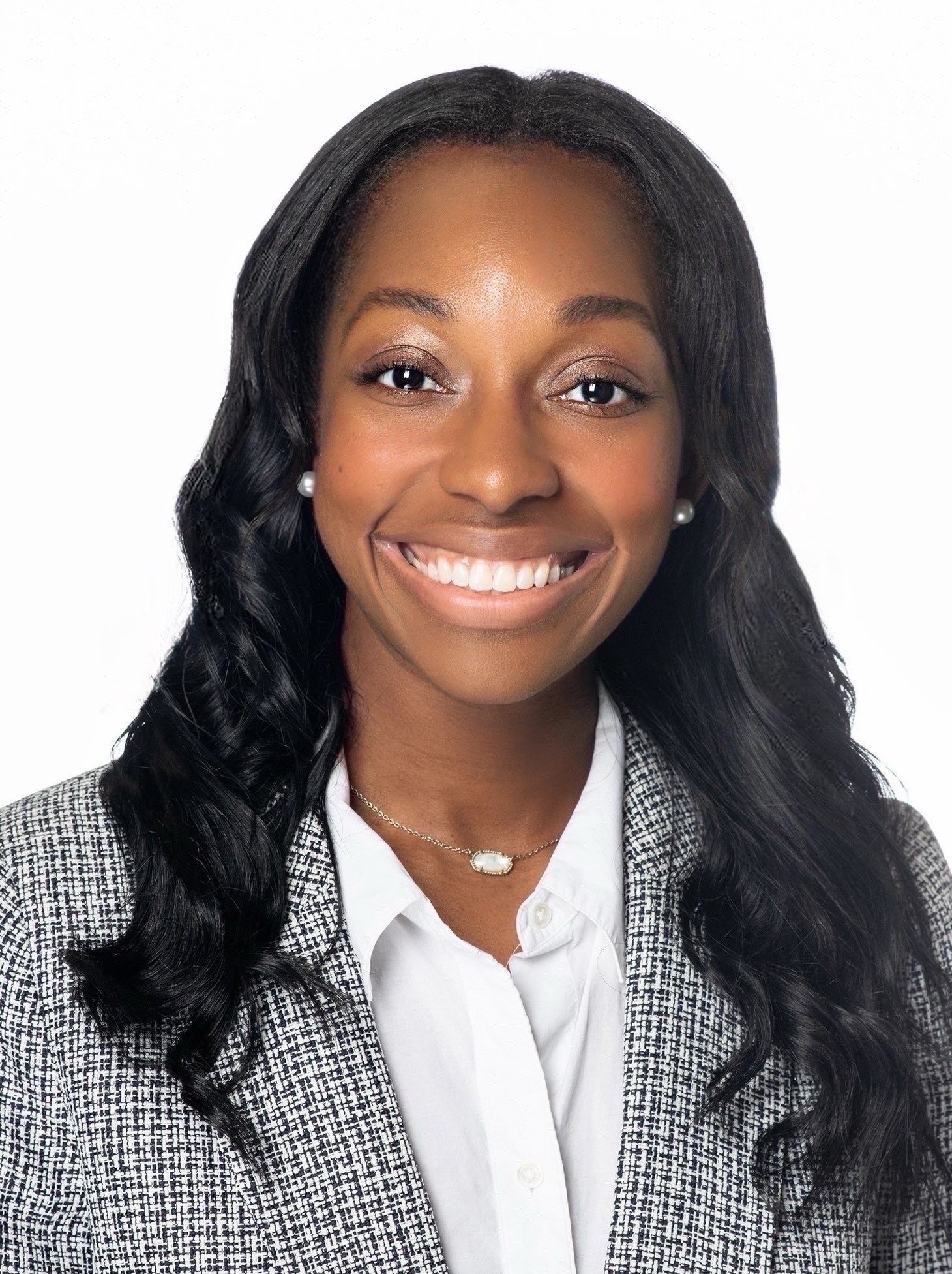 Photograph of TCU alumna Angel Guyton smiling toward the camera against a white background, wearing a white collared shirt and a black-and-white checkered blazer.