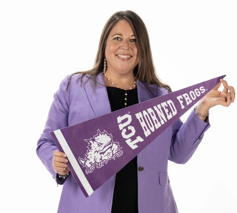 Studio photograph of TCU Dean of Admission Mandy Castro, wearing a purple sports jacket and black dress, holding a purple pennant with white text reading 