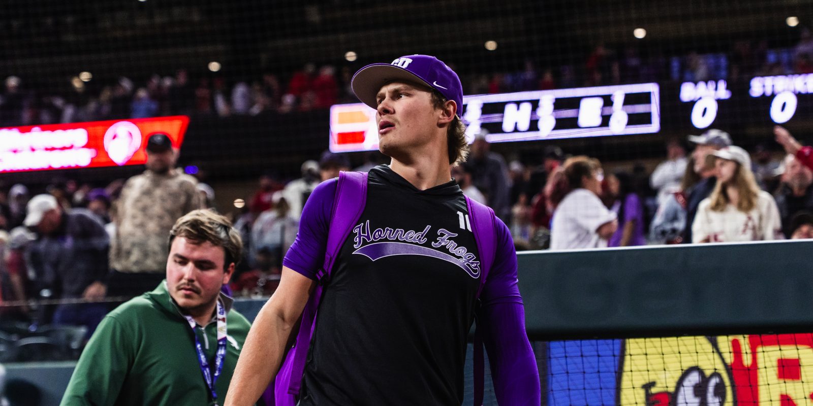 Sawyer Strosnider in a TCU Horned Frogs purple and black uniform stands on the field in a packed stadium, with arena scoreboards and crowd visible behind him.