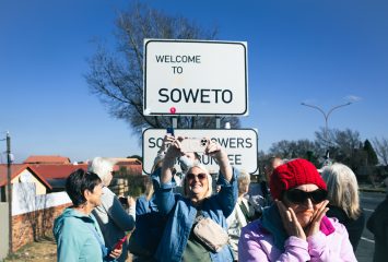Traveling Frogs members Shirley Arsenault, Laura Grimm and Colleen Kleuser photograph the welcome sign at the entrance to Soweto, the Johannesburg neighborhood that was the heart of South Africa's anti-apartheid movement.