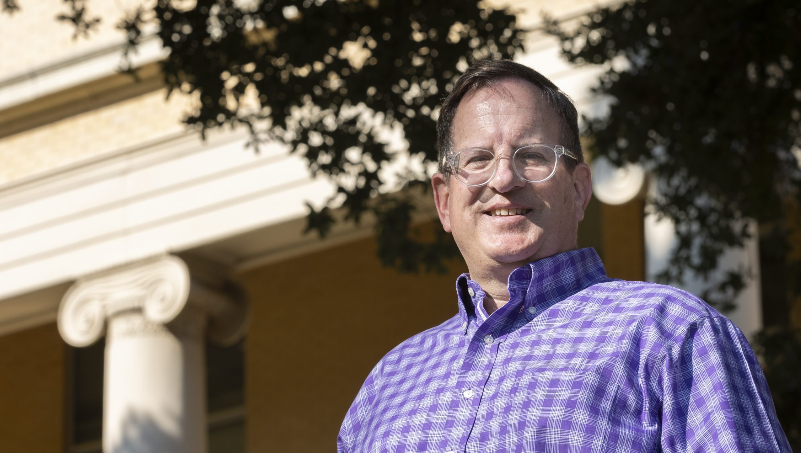 Ashley Tull stands outdoors on the TCU campus with classical architecture visible in the background.