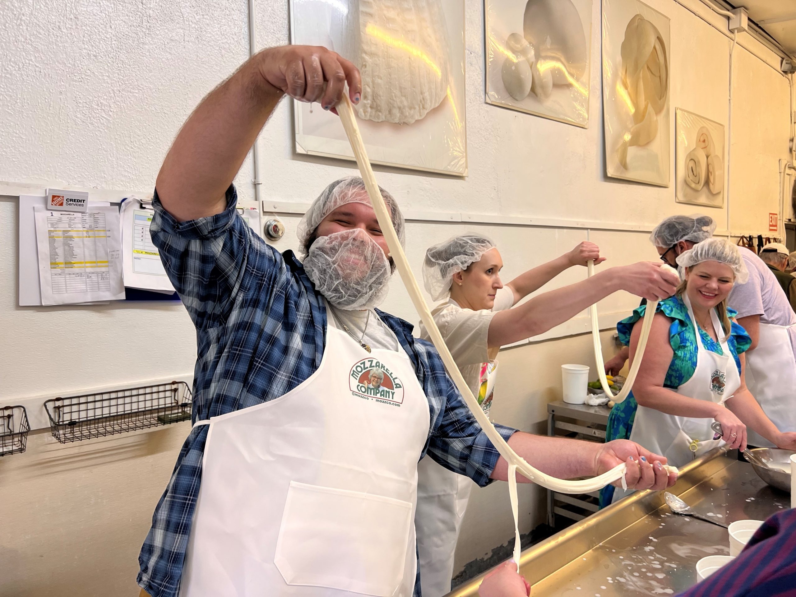 Participants stretching fresh mozzarella during a hands-on cheesemaking class at Mozzarella Company in Dallas.