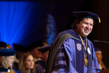 Daniel W. Pullin in purple academic regalia smiling at podium during TCU chancellor inauguration ceremony.