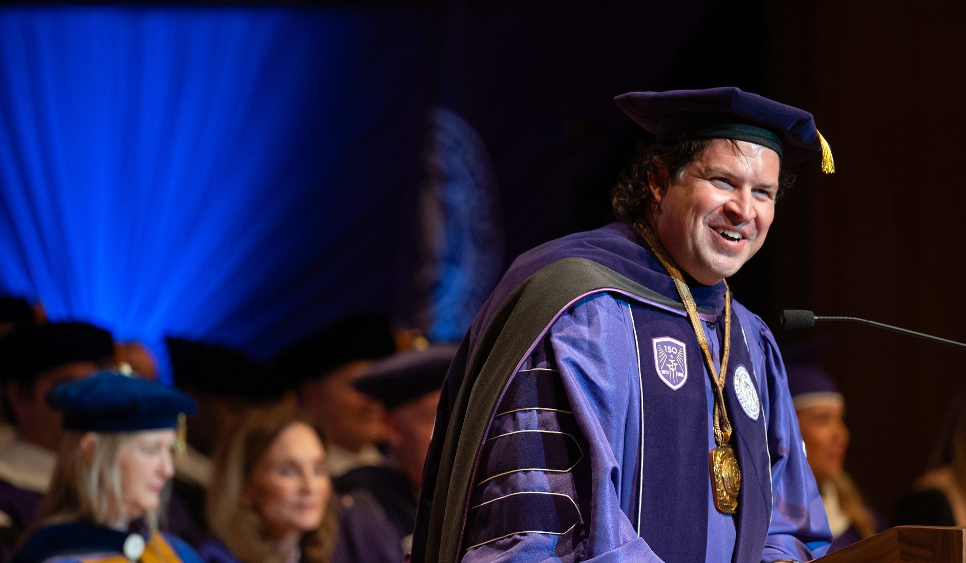Daniel W. Pullin in purple academic regalia smiling at podium during TCU chancellor inauguration ceremony.