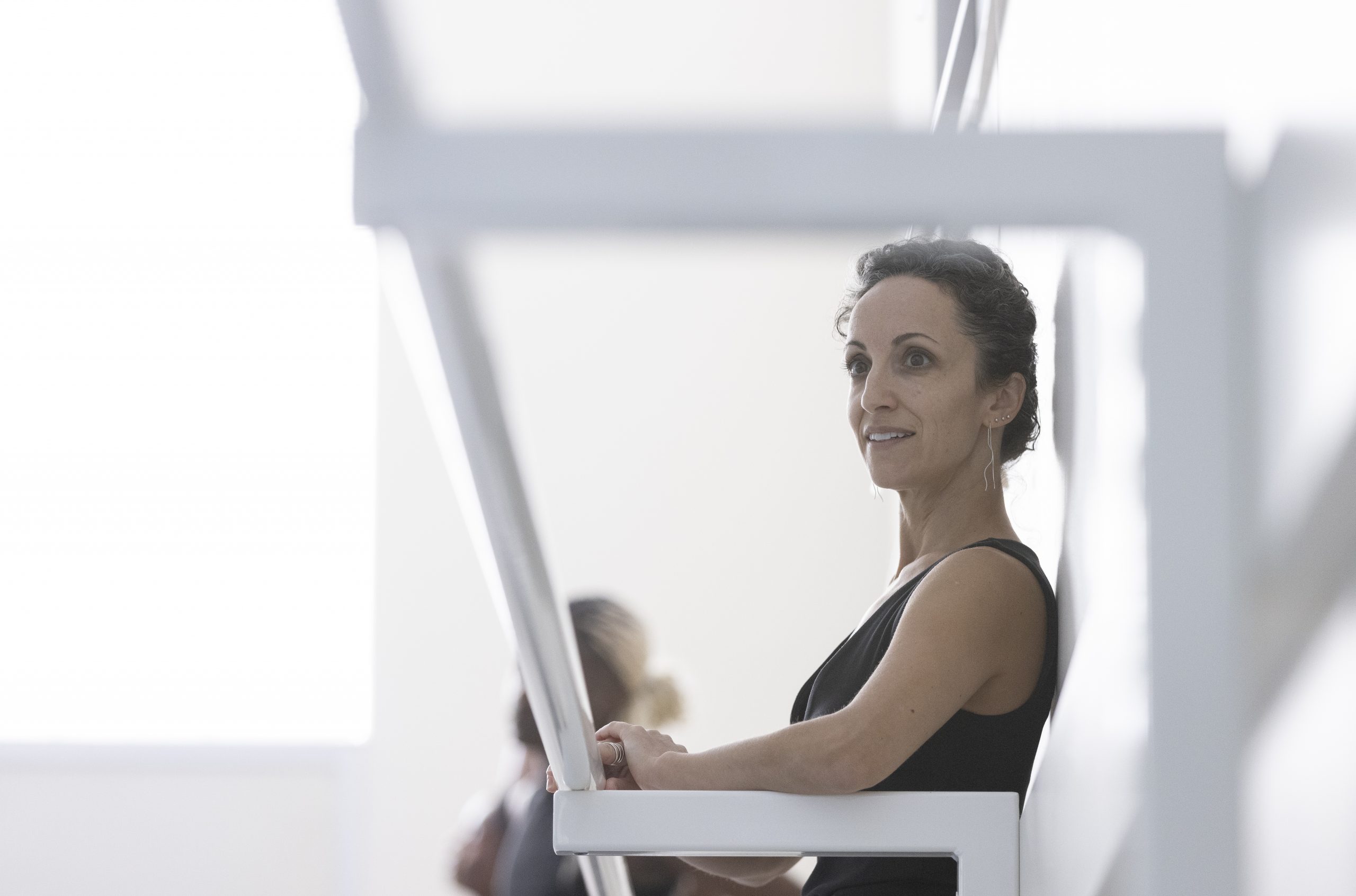 Jessica Zeller sits in a dance studio, framed by ballet barres in the foreground, during a class at TCU.