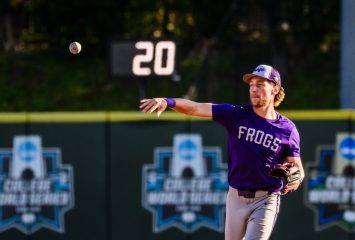 TCU Horned Frogs baseball player Cole Cramer in a purple "Frogs" jersey and gray pants makes a throw across the infield during warm-ups or a game, with College World Series appearance banners for 2016, 2017, and 2023 visible on the outfield wall behind him.
