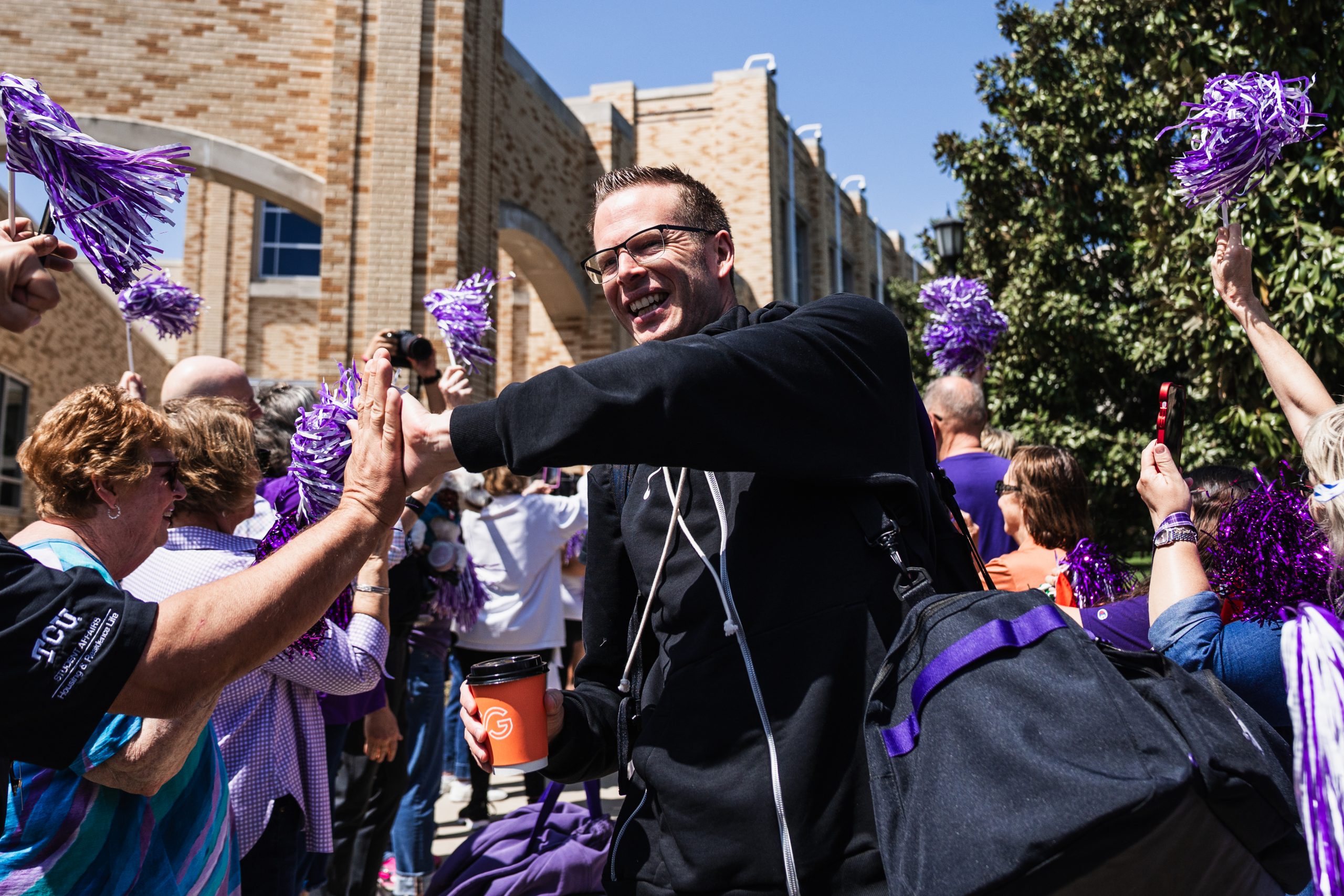 TCU women's basketball head coach Mark Campbell high-fives fans during the team's send-off to Sacramento ahead of the Sweet 16.