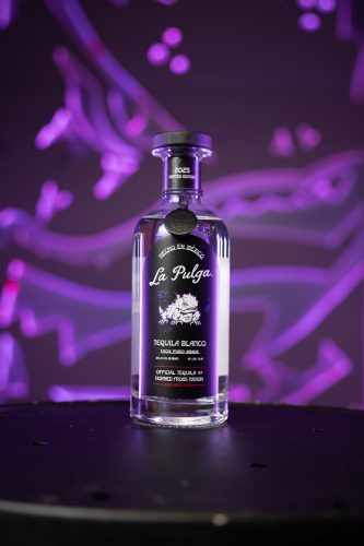 A bottle of La Pulga Tequila Blanco, labeled 'Official Tequila of Horned Frogs Nation' and '2025 Limited Edition,' displayed against a purple-lit background.