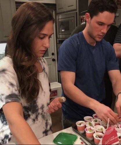 Sophia Karbowski and Austin Patry prepare acai bowls in a kitchen as college students.