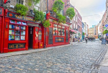 The bright red facade of The Temple Bar pub on a cobblestone street in Dublin, Ireland.