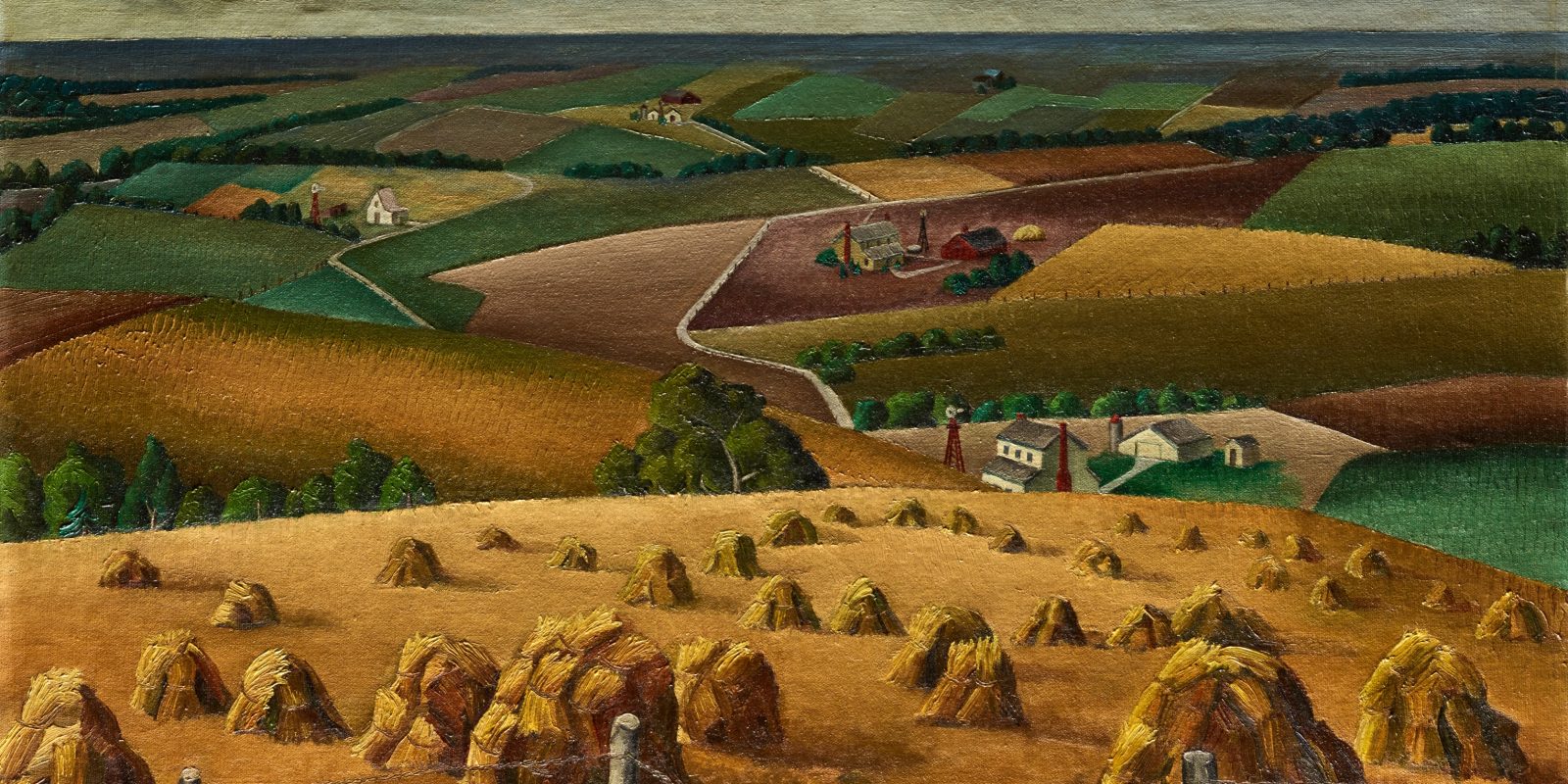A 1937 painting by American artist Florence E. McClung titled “Squaw Creek Valley,” depicting a sweeping rural landscape. In the foreground, golden wheat shocks (bundled sheaves) are arranged in rows across a harvested field, framed by a barbed wire fence with weathered wooden posts. The middle ground shows a patchwork of cultivated fields in greens, browns, and ochres, with small farmsteads — white houses with red barns and windmills — nestled among winding pale roads. The composition recedes into rolling hills with more fields and scattered trees, leading to a hazy blue-gray horizon under a cloudy sky. The style is characteristic of American Regionalist painting from the 1930s, with stylized, slightly flattened forms and a strong sense of agricultural rhythm and pattern.