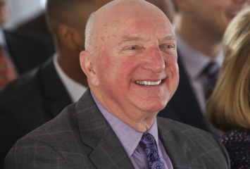 Thomas Gregory Sumner smiles during a TCU event, wearing a dark gray suit, lavender shirt and purple patterned tie.