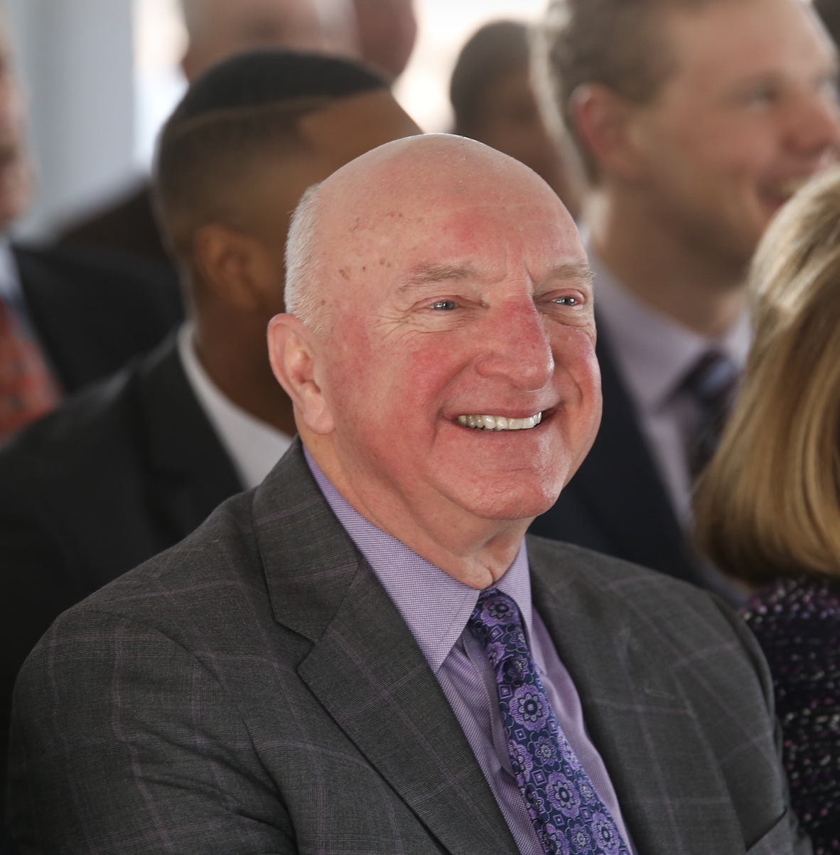 Thomas Gregory Sumner smiles during a TCU event, wearing a dark gray suit, lavender shirt and purple patterned tie.