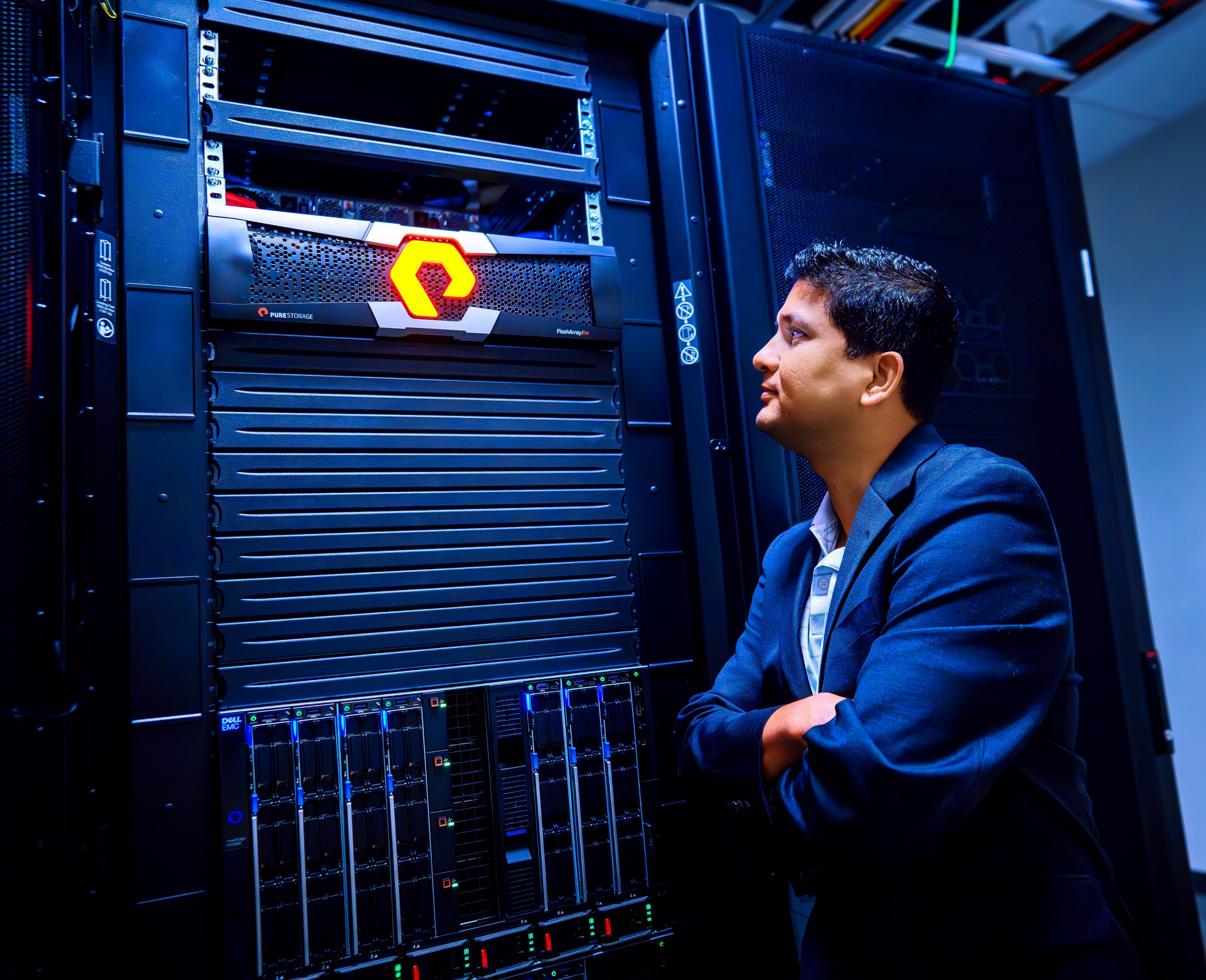 TCU professor Robin Chataut stands beside a large computer server in a data center, looking toward the equipment with his arms crossed.