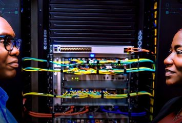 Two people stand facing each other on either side of a server rack filled with colorful network cables, with digital circuitry graphics overlaid across the image.